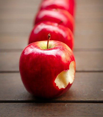 Line of apples with one partially eaten